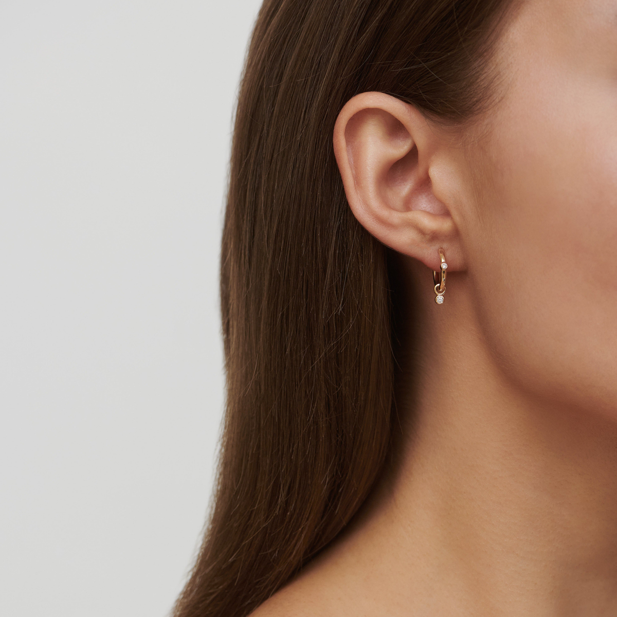 Modell bærer Purity Medium Hoop i øret, stylet med et perle ear pendant