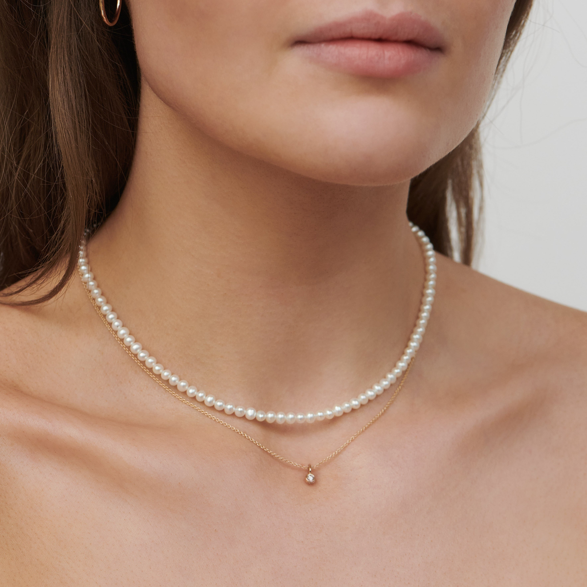 Modell har på seg en perlekjede lagvis med en tynn gullkjede med diamantanheng
