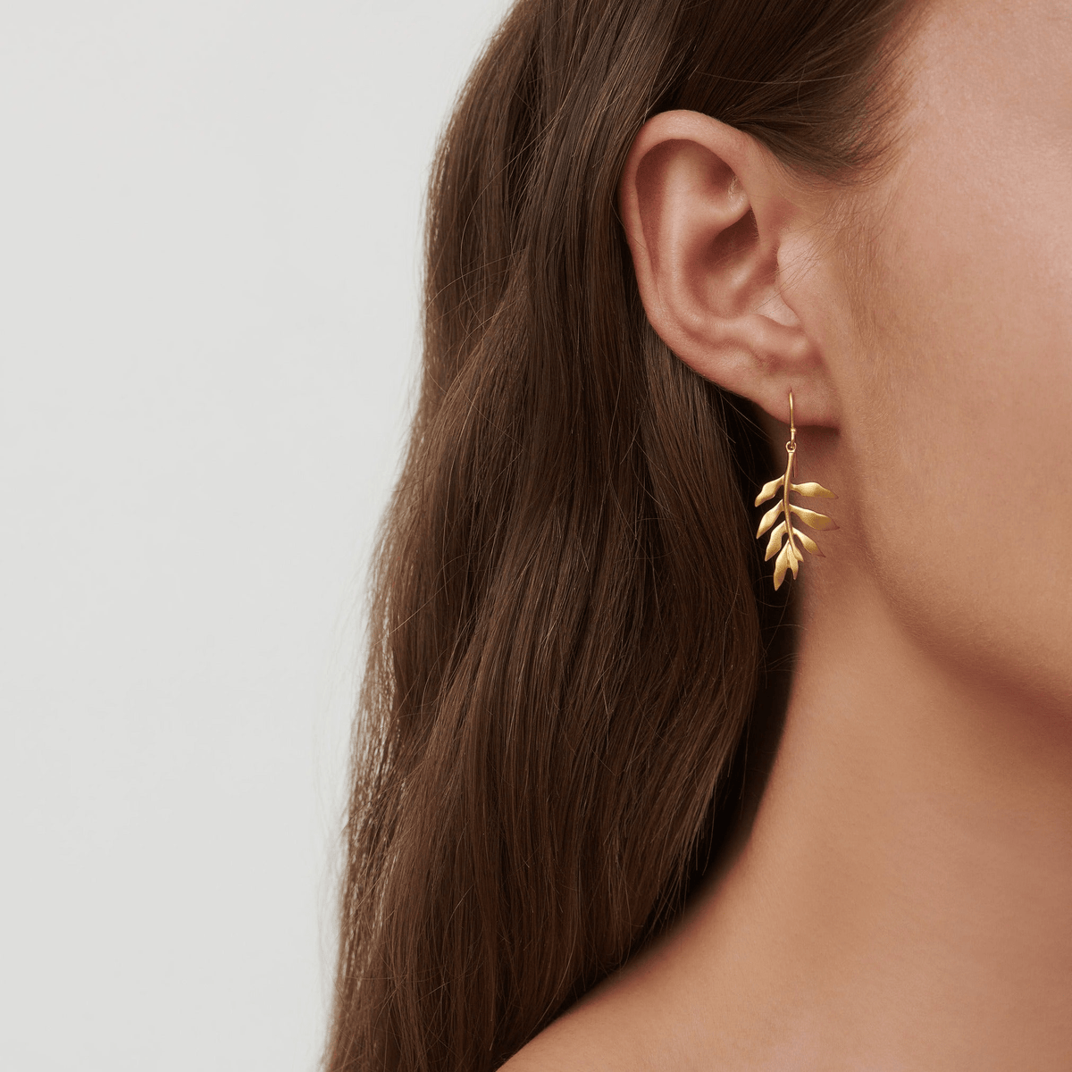 Modell bærer Tree Of Life Earrings med logo-anheng i øret