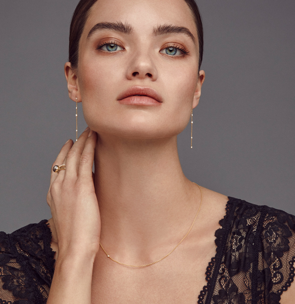 Modell med en tynn gullhalskjede fra Julie Sandlau med en synlig diamant nær kragebenet, samt øredobber og ring som ikke er en del av dette produktet
