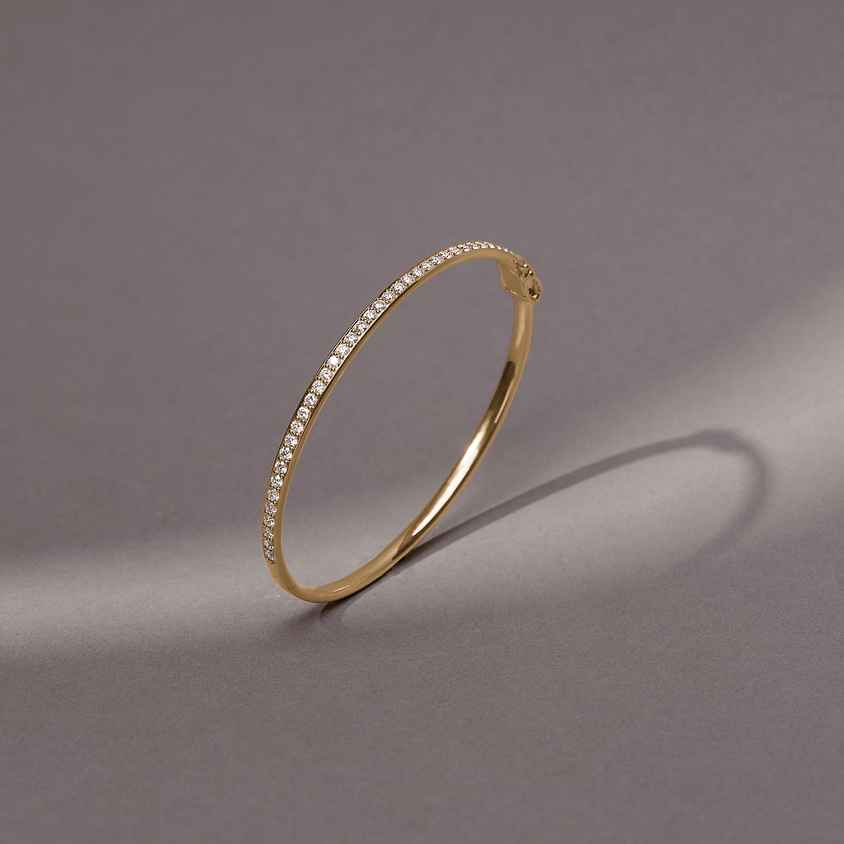 Elegance Armbånd i 18K gull med diamanter, nærbilde på grå bakgrunn.