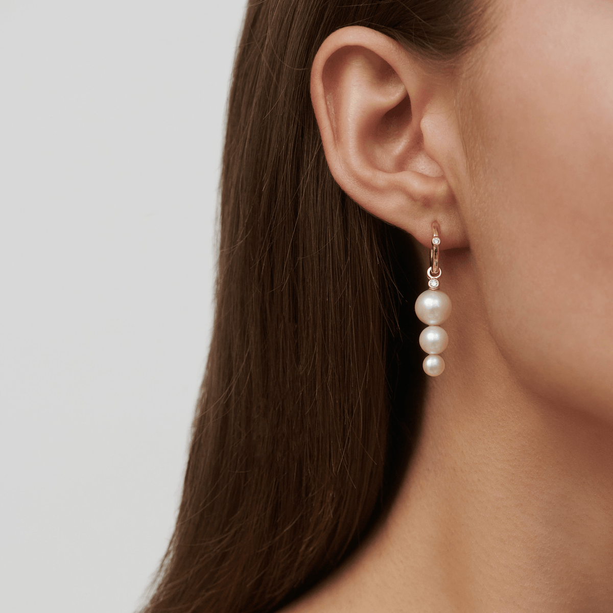 Modell bærer Purity Medium Hoop i øret, stylet med et flerlags perle ear pendant