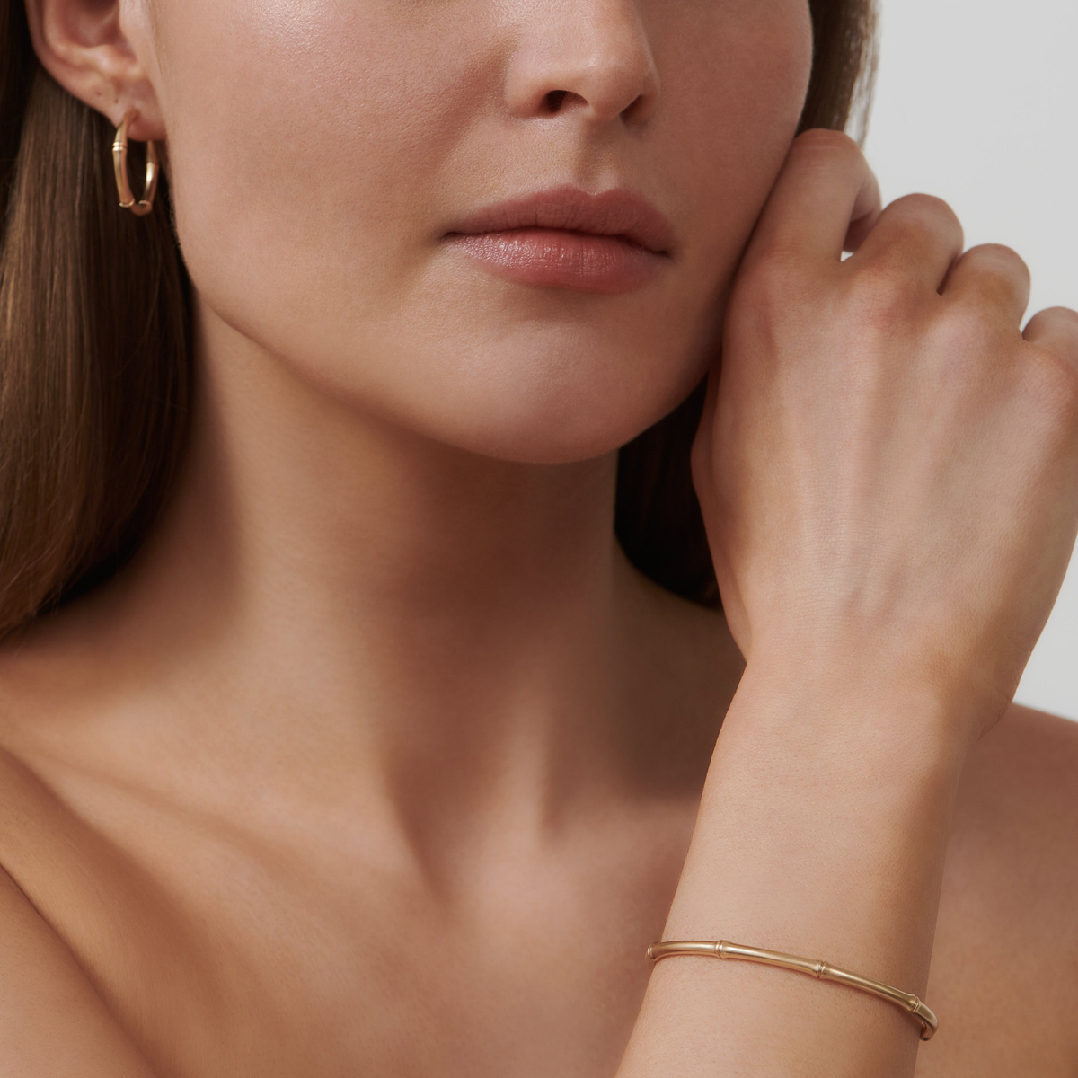 Modell har på seg Bamboo Cuff og øredobber fra Julie Sandlau i gull