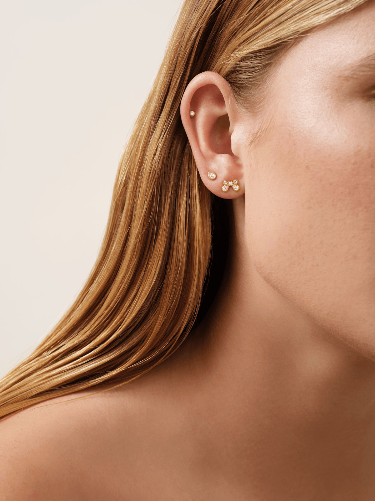 Modell baerer White Wisteria Drop Earstud nederst i oret, stylet sammen med en cartilage-stud og en tre-steins orestikk