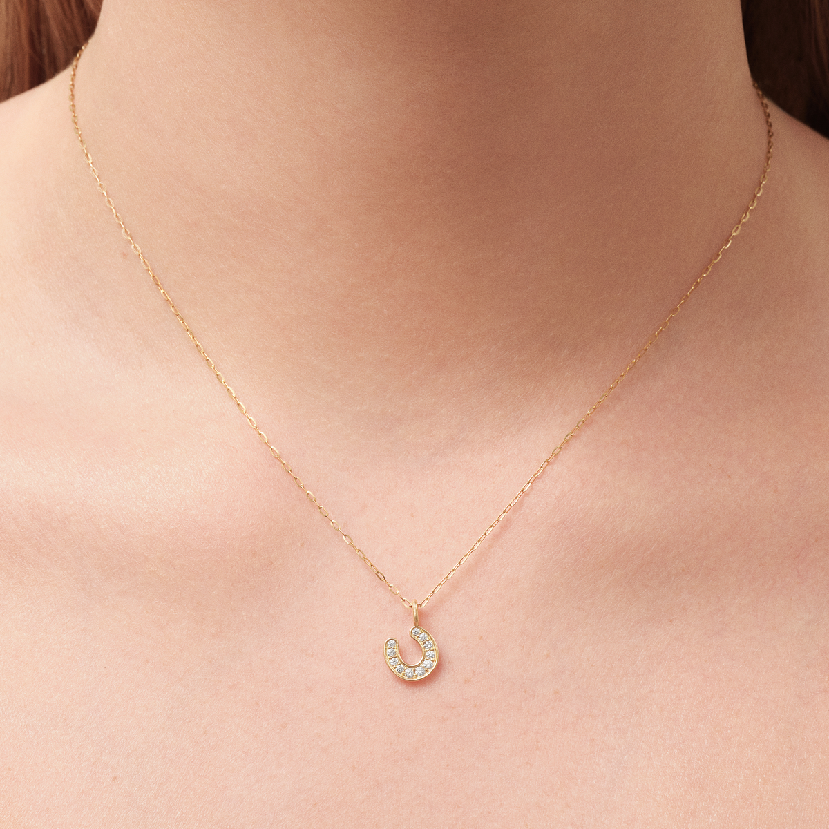 Modell bærer Horseshoe Pendant i 14K gull på tynn gullkjede
