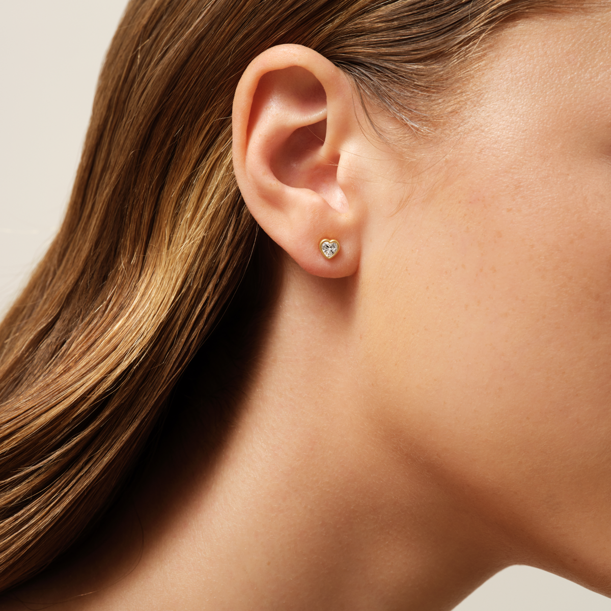 Modell bærer Amorina ørestikk med hjerteformet cubic zirconia på øret