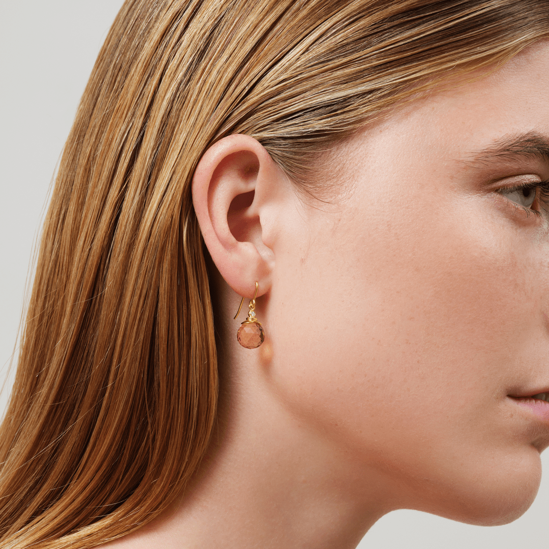Modell bærer Berry Earrings med ferskenfarget facettslipt krystall i forgylt sølv