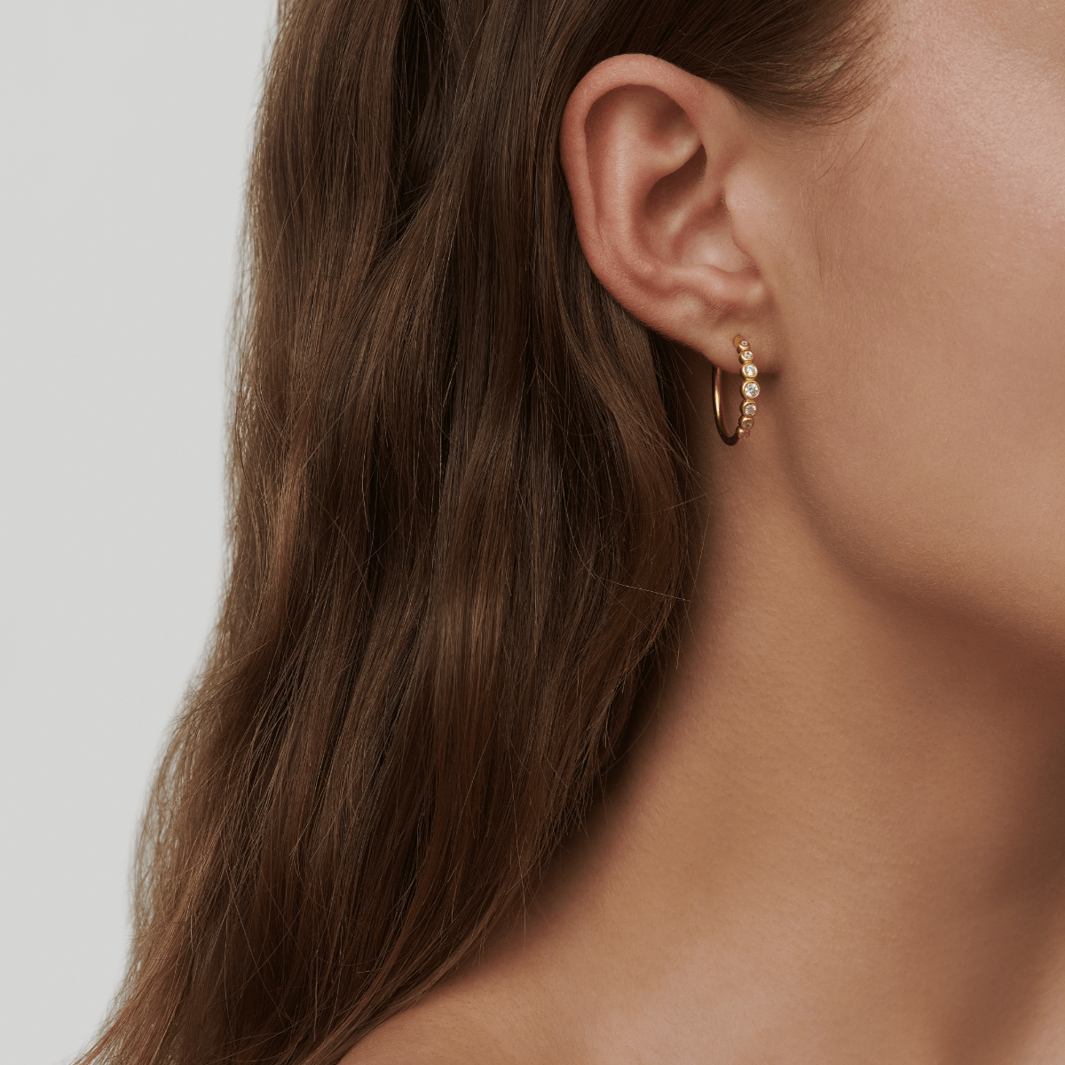 Modell bærer Grace Hoops creoler i forgylt sølv med zirkoner, close-up på øret