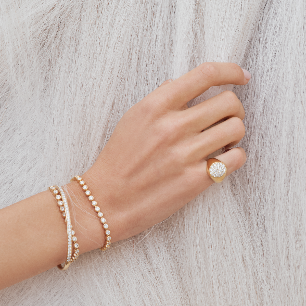 Hånd med Elegance Armbånd stablet sammen med annet armbånd og ring, som ikke er en del av dette produktet.