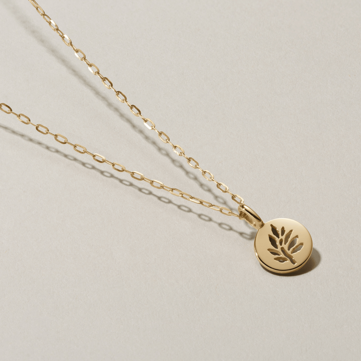 Legacy Pendant i gull på kjede, fotografert som flatlay